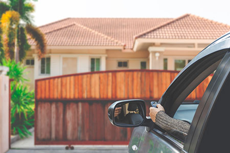 person in a car activating a sliding gate with a remote control